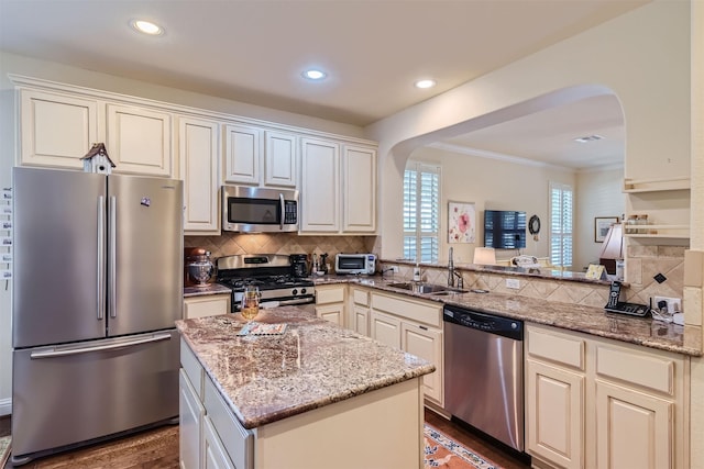 kitchen featuring a center island, kitchen peninsula, sink, appliances with stainless steel finishes, and light stone counters