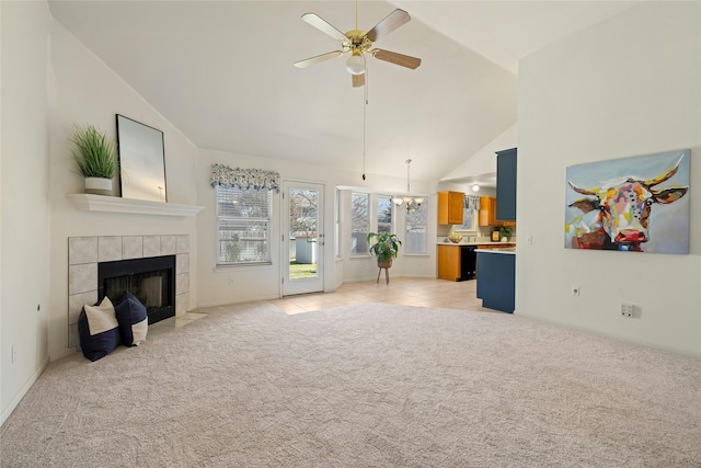 living room featuring light carpet, ceiling fan with notable chandelier, a tiled fireplace, and high vaulted ceiling