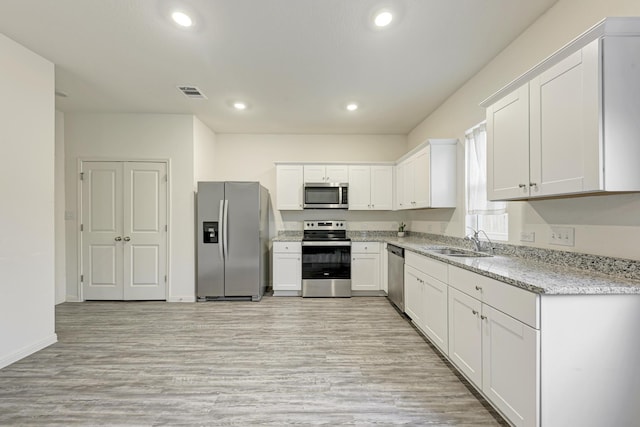 kitchen with light stone countertops, sink, white cabinetry, and stainless steel appliances