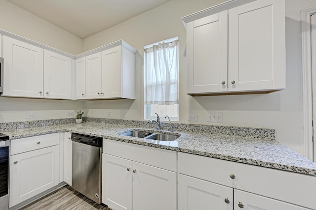 kitchen featuring stainless steel dishwasher, white cabinets, light stone counters, and sink