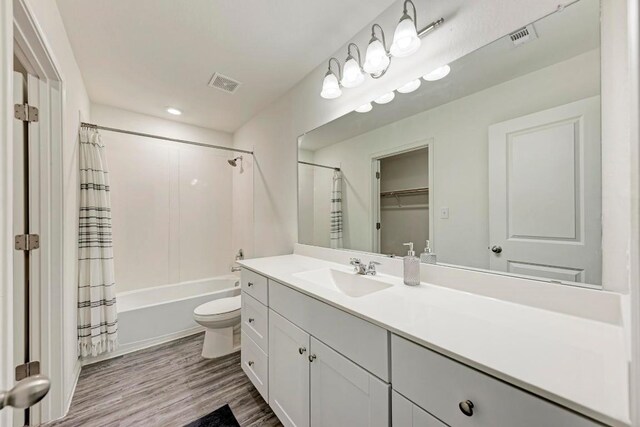 full bathroom featuring toilet, shower / bath combination with curtain, wood-type flooring, and vanity