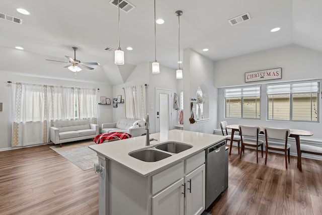 kitchen featuring lofted ceiling, decorative light fixtures, an island with sink, sink, and stainless steel dishwasher