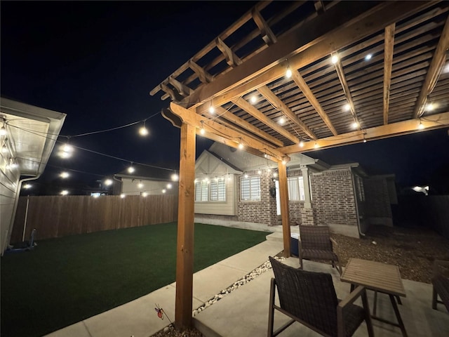 patio at night featuring a yard and a pergola