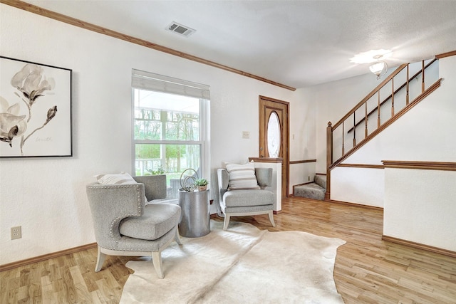 sitting room with ornamental molding and light wood-type flooring