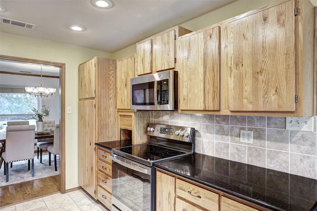 kitchen with light brown cabinetry, backsplash, light tile patterned floors, a notable chandelier, and stainless steel appliances