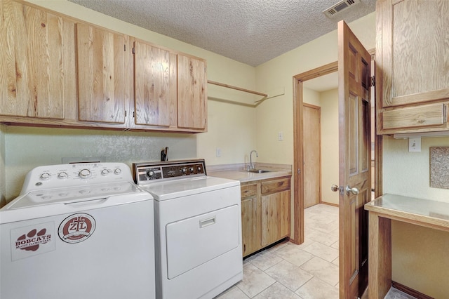 washroom featuring separate washer and dryer, sink, cabinets, light tile patterned floors, and a textured ceiling