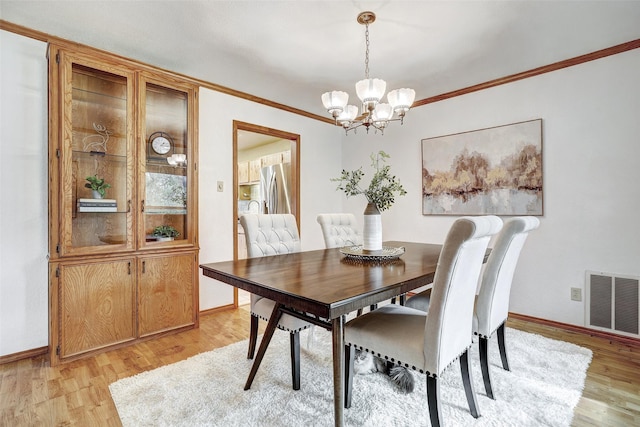 dining space with crown molding, light hardwood / wood-style flooring, and a notable chandelier