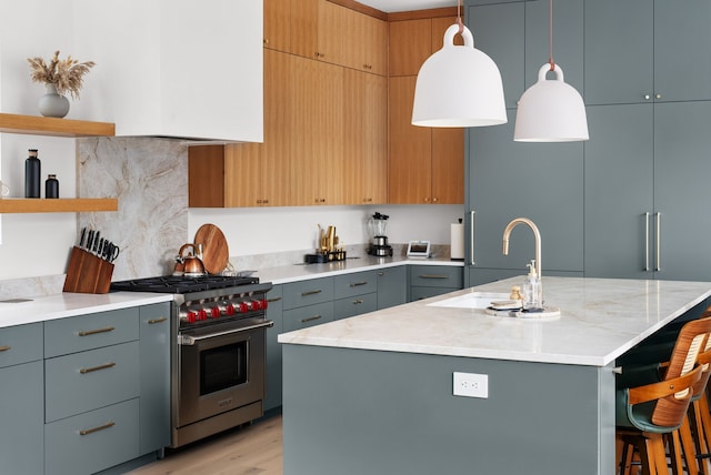 kitchen with a center island with sink, a breakfast bar, sink, hanging light fixtures, and luxury range