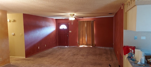 carpeted foyer featuring ceiling fan and a textured ceiling