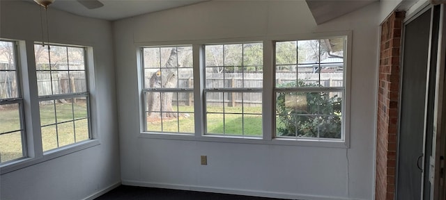 unfurnished sunroom with ceiling fan