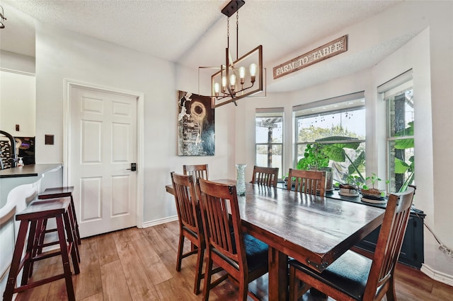 dining area featuring light hardwood / wood-style floors, a textured ceiling, and a notable chandelier