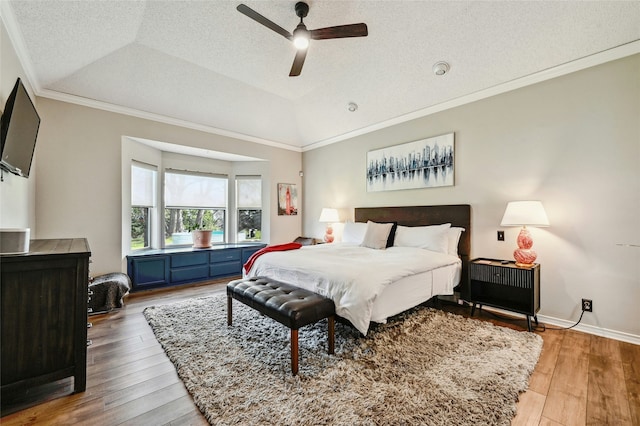 bedroom featuring hardwood / wood-style floors, lofted ceiling, ornamental molding, a raised ceiling, and ceiling fan