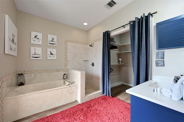 bathroom featuring a textured ceiling, shower with separate bathtub, and hardwood / wood-style flooring