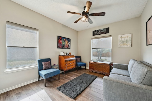 living area featuring ceiling fan, hardwood / wood-style floors, and a textured ceiling