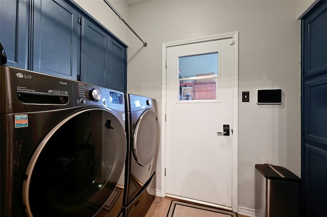 laundry area featuring cabinets, hardwood / wood-style floors, and washing machine and clothes dryer