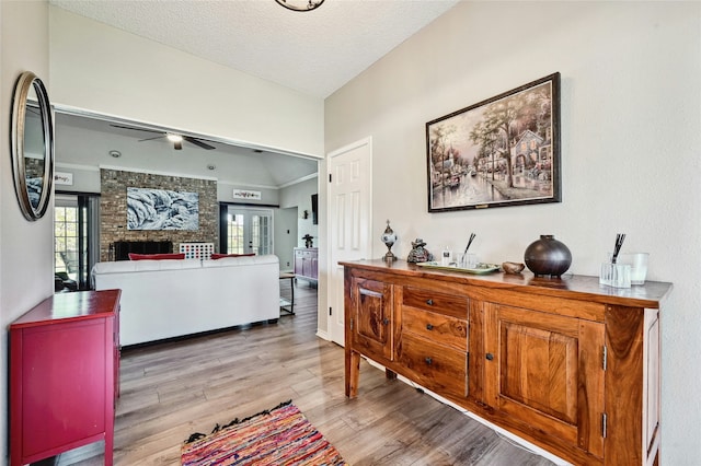 interior space featuring ceiling fan, a fireplace, a textured ceiling, and light hardwood / wood-style floors