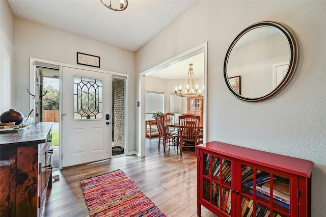 entryway with wood-type flooring, an inviting chandelier, and a textured ceiling