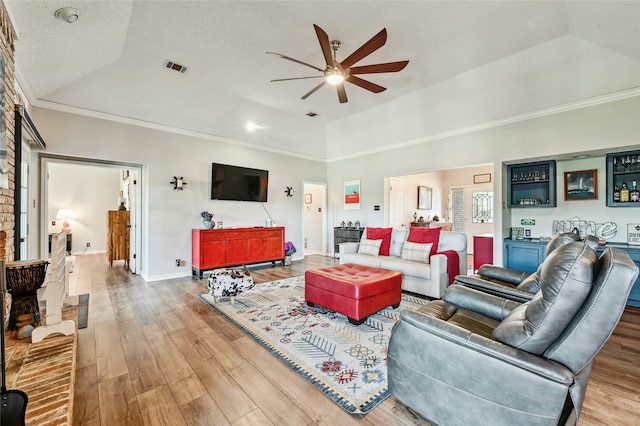 living room with wood-type flooring, lofted ceiling, a raised ceiling, and crown molding