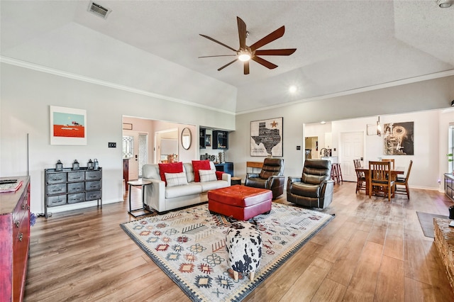 living room featuring ceiling fan with notable chandelier, a textured ceiling, crown molding, and lofted ceiling