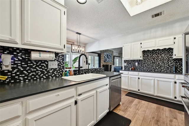 kitchen featuring sink, pendant lighting, white cabinets, and dishwasher