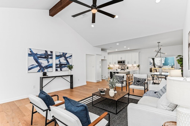 living room featuring ceiling fan, vaulted ceiling with beams, sink, and light hardwood / wood-style flooring