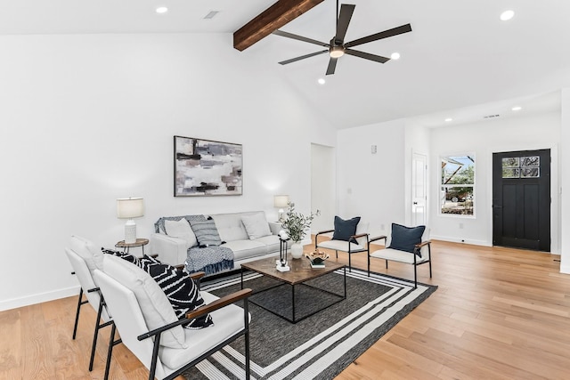 living room featuring light wood-type flooring, ceiling fan, and vaulted ceiling with beams