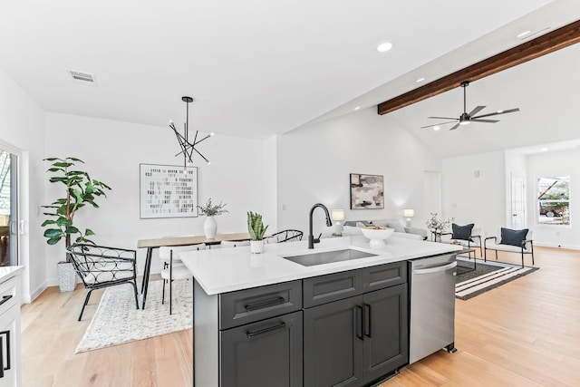 kitchen with a center island with sink, light wood-type flooring, hanging light fixtures, stainless steel dishwasher, and sink