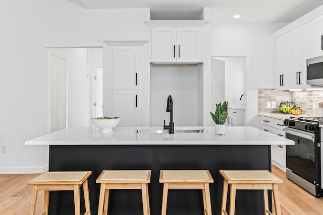 kitchen featuring appliances with stainless steel finishes, a kitchen bar, and white cabinetry