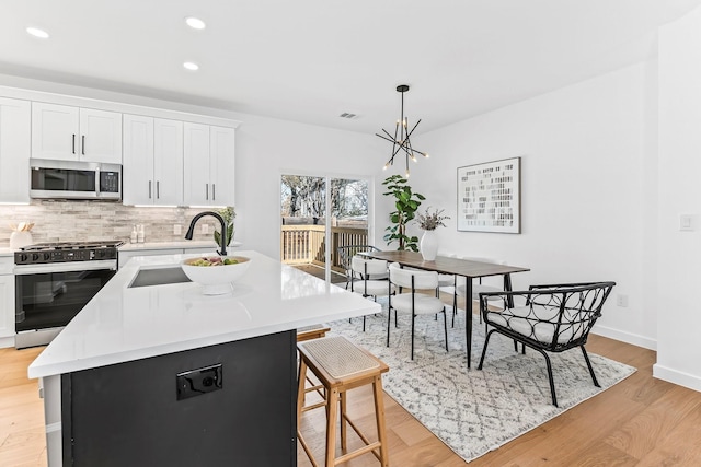 kitchen with white cabinetry, gas stove, a notable chandelier, hanging light fixtures, and a center island