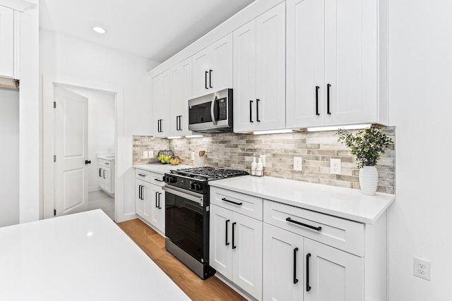 kitchen with decorative backsplash, white cabinetry, and gas stove