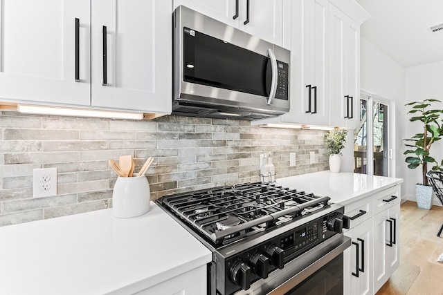 kitchen with tasteful backsplash, light wood-type flooring, stainless steel appliances, and white cabinetry