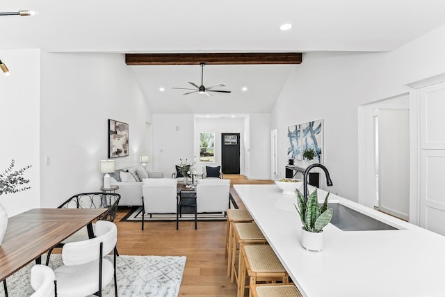 dining area featuring ceiling fan, hardwood / wood-style floors, sink, beamed ceiling, and high vaulted ceiling