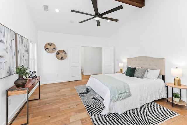 bedroom with ceiling fan, high vaulted ceiling, beam ceiling, and light hardwood / wood-style flooring