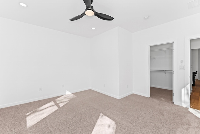 unfurnished bedroom featuring ceiling fan, a walk in closet, a closet, and carpet floors