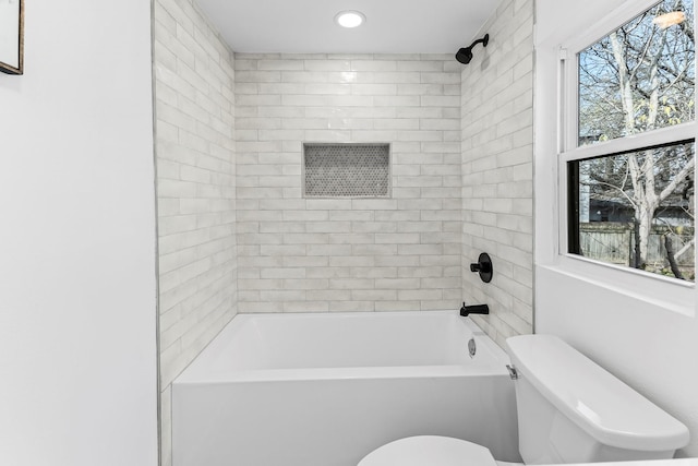 bathroom with tiled shower / bath combo and toilet