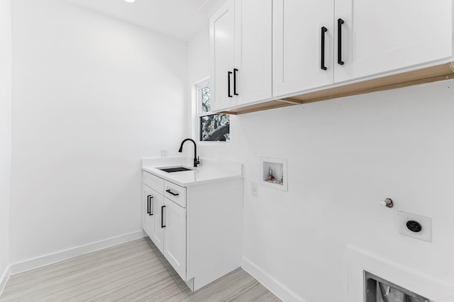 clothes washing area with cabinets, sink, hookup for a washing machine, hookup for an electric dryer, and light hardwood / wood-style flooring