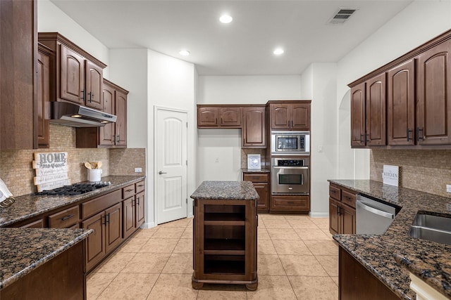 kitchen with light tile patterned floors, dark stone counters, stainless steel appliances, and dark brown cabinets