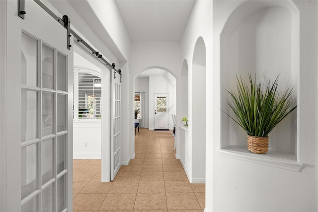 hall with light tile patterned floors and a barn door