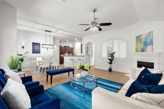 tiled living room featuring vaulted ceiling, ceiling fan, and sink