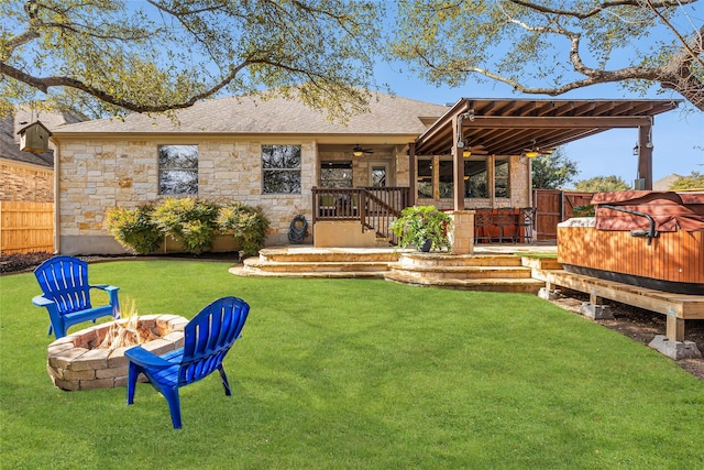 back of house featuring ceiling fan, a yard, a hot tub, and a fire pit