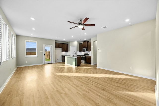 unfurnished living room featuring ceiling fan, baseboards, a sink, and recessed lighting