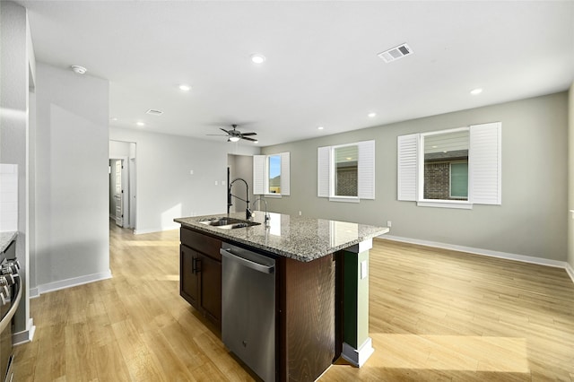 kitchen with a sink, visible vents, stainless steel dishwasher, light stone countertops, and a center island with sink