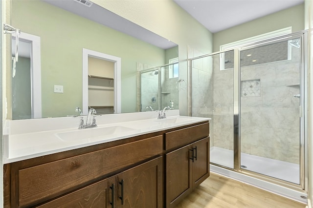 full bath featuring double vanity, a shower stall, wood finished floors, and a sink