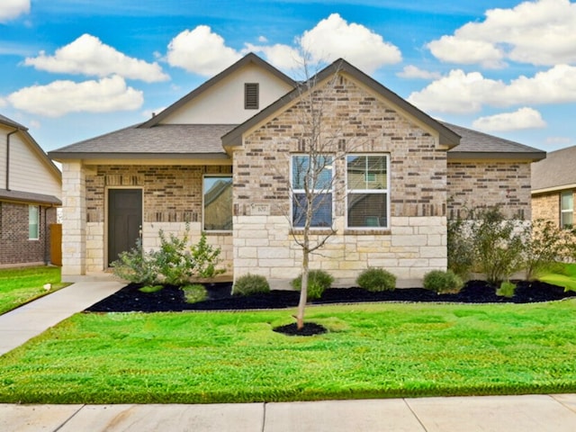 view of front of property with stone siding, a front lawn, and roof with shingles