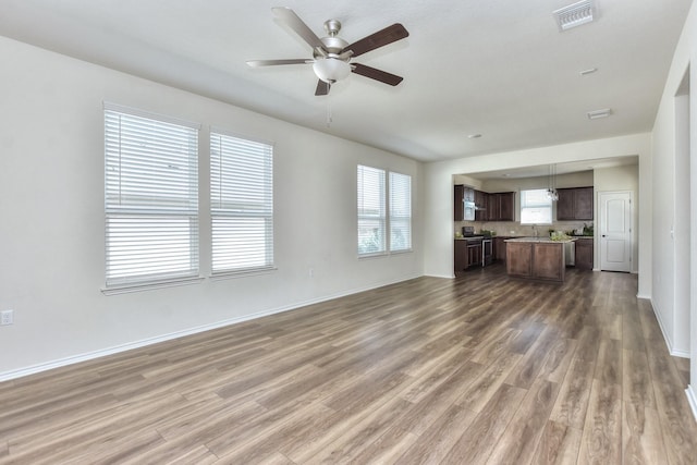 unfurnished living room featuring ceiling fan and dark wood-type flooring