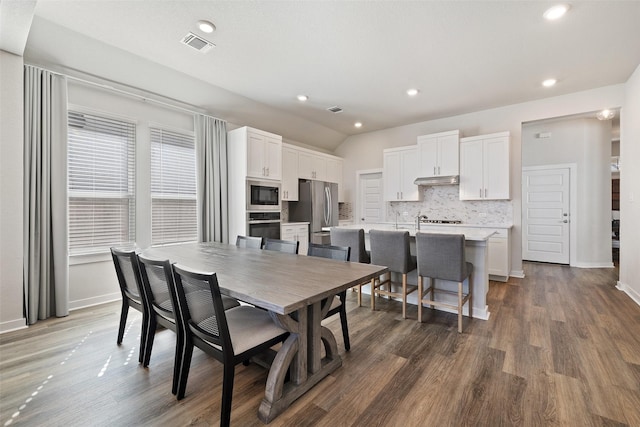 dining room with vaulted ceiling, dark wood-type flooring, and sink