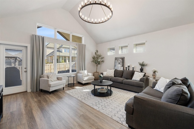 living room featuring high vaulted ceiling, a notable chandelier, and hardwood / wood-style flooring