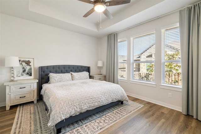 bedroom with ceiling fan, dark hardwood / wood-style flooring, and a raised ceiling