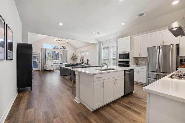 kitchen with white cabinetry, stainless steel appliances, decorative backsplash, a kitchen island with sink, and vaulted ceiling