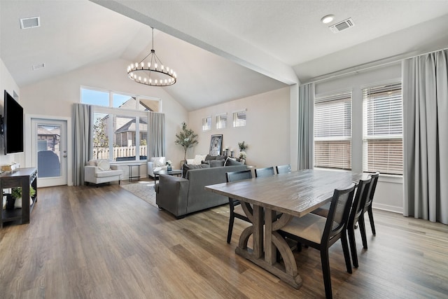 dining space featuring an inviting chandelier, a wealth of natural light, lofted ceiling, and hardwood / wood-style floors